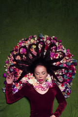 Conceptual studio portrait girl. Artificial flowers and a green background.