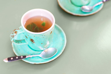 Green mint cup of mint tea on table toned green with copy space.