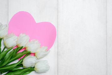 Spring tulip flowers and paper card on gray stone table from above in flat lay style. Greeting for Women's or Mothers Day