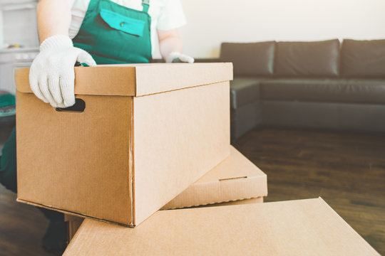 Delivery man loading cardboard boxes for moving to an apartment. professional worker of transportation, male loaders in overalls