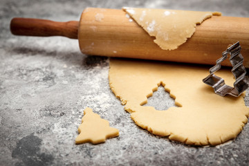 Cookie dough and rolling pin on grey table, christmas tree shaped cutter