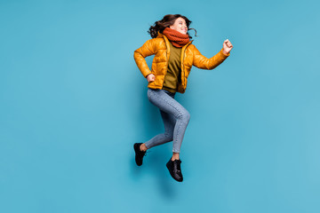 Full length photo of crazy millennial lady jumping high running speed shopping season discounts wear stylish windbreaker jeans scarf pullover isolated blue color background © deagreez