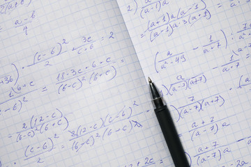 Algebraic calculations in open graph notebook with black pen. White graph paper with math...