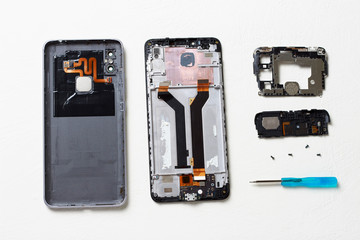 Disassembled broken smartphone on a white table, top view