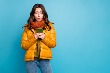 Photo of amazing millennial lady hold telephone read positive comments enjoy followers wear stylish autumn windbreaker jeans scarf isolated blue color background © deagreez
