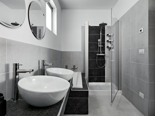 interior view of a modern bathroom in foreground two countertop washbasin on the background the masonry shower box with glass door