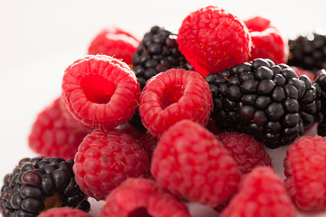 handful of raspberry and blackberry berries on white background