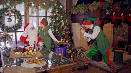 Santa Claus making photos. Santa Claus photographing in red traditional outfit with elves