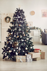 Image of beautiful decorated Christmas tree with Christmas presents under it in the living of the house