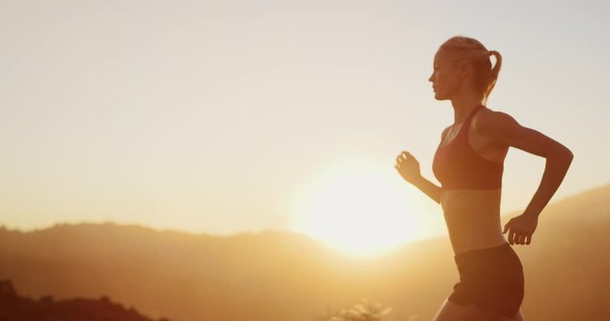 Active woman running at sunset outdoors in the mountains, determined woman running and achieving her sports fitness goals