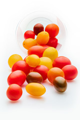 Colorful cherry tomatoes (red, garnet and yellow), fresh and raw. In plastic jar. Isolated on white background