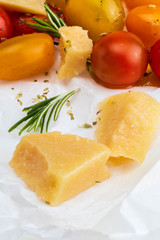 Close-up of sheep cheese with rosemary and cherry colored tomatoes (red, garnet and yellow), fresh and raw. Homemade and rustic look with olive oil and spices.