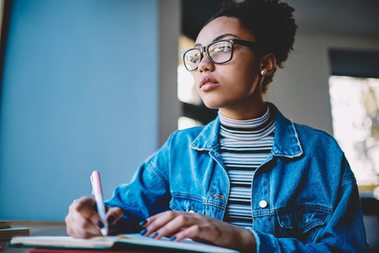 Contemplative female student in optical eyewear for vision correction thoughtful looking away and thinking about idea for essay during time for autodidact, pensive teenager learning on publicity area