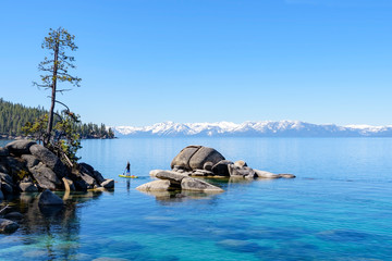 Kayaks in the lake, paddle boarders paddling on the turquoise color water  in Lake Tahoe with view...
