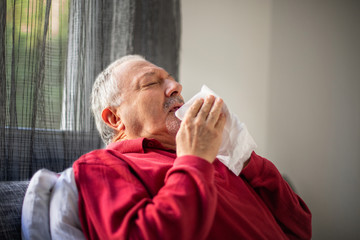 A senior flu man is lying on the bed with fever