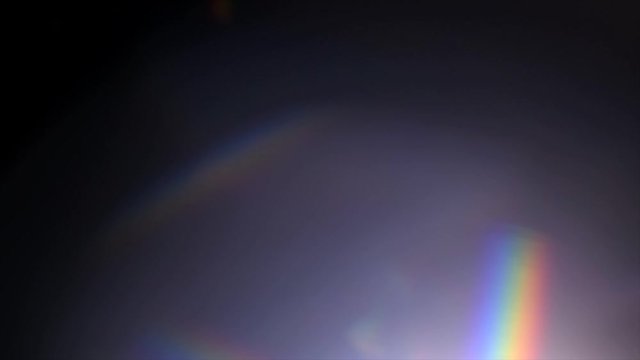 Lens Flare, Abstract Bokeh Lights Moving. Leaking Reflection of a Glass, Crystal, Defocused Shining Colorful rainbow Light Leaks, Rays on Black Background. 4K UHD video, slow motion