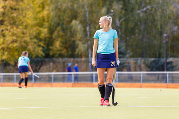 Young female hockey player with stick on the field