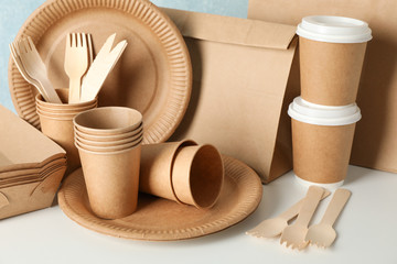Eco - friendly tableware and paper bag on wooden table, close up