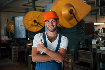 Positive guy. Portrait of engineer in metallurgical factory in protective helmet