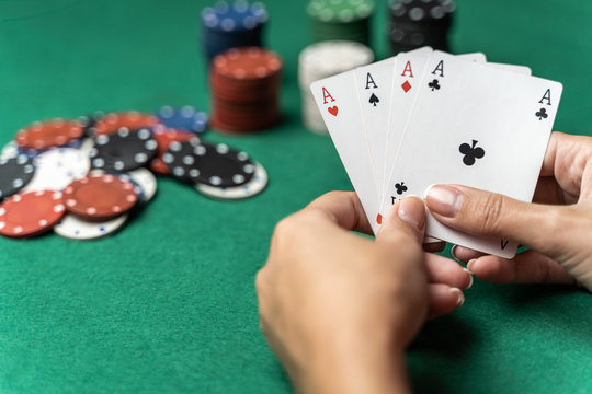 Stack of chips and woman hand with four aces on the table. Poker game concept