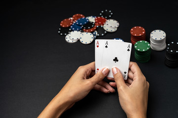Stack of chips and woman hand with two aces on the table. Poker game concept