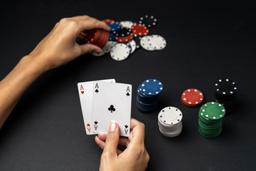 Stack of chips and woman hand with two aces on the table. Poker game concept