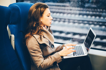 Freelancer girl working with laptop in the train. Business travel or technology concept.
