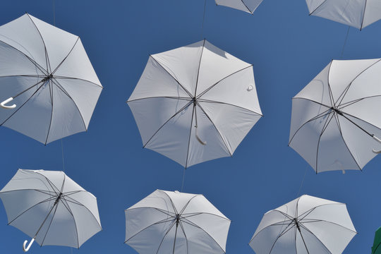 White umbrellas floating in the air with blue sky