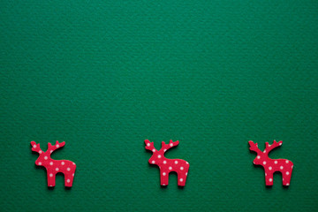 Minimal Christmas concept. Red deer on green textured paper. Close-up. Horizontal orientation. Business cards, menu design, congratulations, decorations. Copy space, flat lay. New Year's idea.