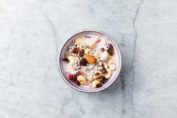 Bowl of granola with yogurt, nuts, raisins, cranberries and chia seeds. Concept for a tasty and healthy meal. Stone background. Top view. Copy space.