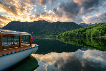 Lake bohinj beautiful sunset during spring season with amazing reflection off the lake and a traditional boat and boat hut