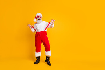 Full length photo of cool crazy santa claus in red hat enjoy x-mas newyear miracle jolly party celebration pull suspenders wear shirt stand over shine color background