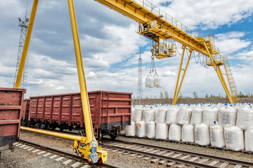 Cargo crane lifts two large bags of ammonium nitrate. Big yellow gantry crane. - obrazy, fototapety, plakaty