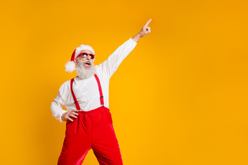 Portrait of funny crazy santa claus hipster in red hat fun christmas x-mas party celebrate newyear time dance raise index finger wear shirt suspenders isolated yellow color background