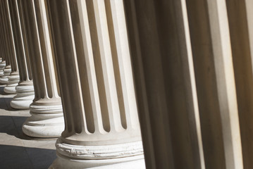 Dramatic sunlit down a colonnade of fluted columns with shadowy architectural texture