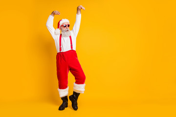 Fototapeta na wymiar Full length photo of crazy funny santa claus in red fairy hat dance raise hands christmas x-mas tradition celebration wear black boots shirt suspenders isolated yellow color background