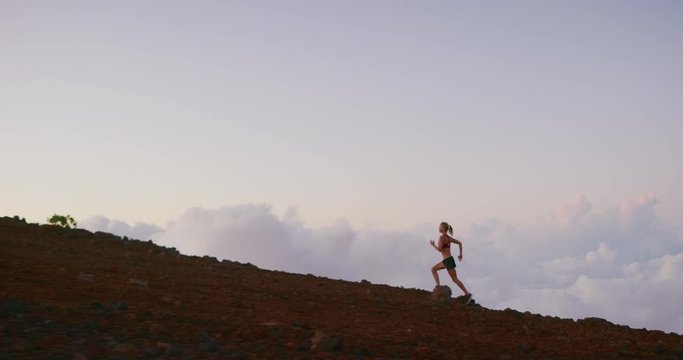 Strong independent woman running up a mountain in the clouds with strength and determination, runner achieving her ultra marathon goals outdoors