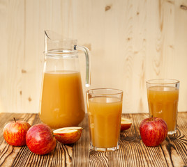 Ripe apples and freshly squeezed juice in glasses on a wooden table