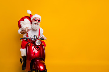 Chritsmas come. Funky crazy grandfather hipster in santa claus hat drive fast scooter hurry x-mas...