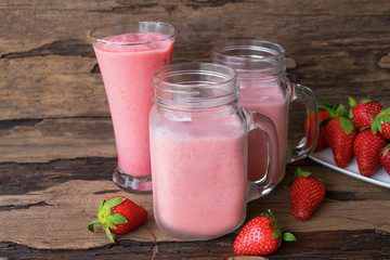 Strawberry smoothies colorful pink fruit juice milkshake blend beverage healthy high protein the taste yummy In glass,drink episode morning on wood background.