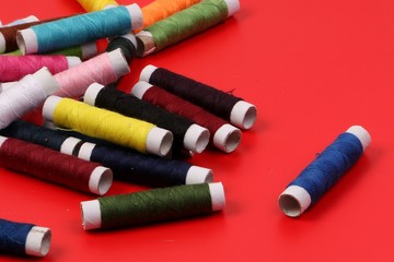pile of colorful sewing rolls lie on a red background
