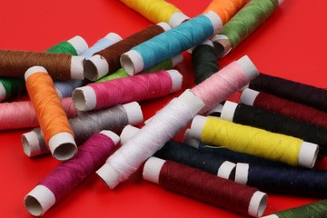 pile of colorful sewing rolls lie on a red background