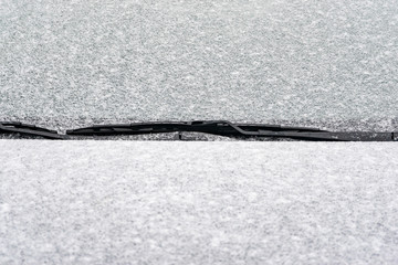 Snow covered car windshield. The beginning of the winter season.