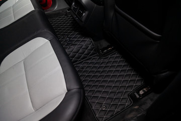 Car 3D handmade rugs with diamond-shaped stitching threads of black color from genuine leather for rear passengers of a vehicle in an interior design workshop. Auto service industry.