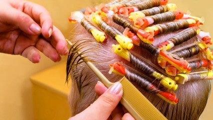 Close-up of the work of a hairdresser curling hair on curlers.