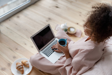 Young woman working on notebook and drinking coffee