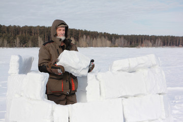 Man building an igloo from snow blocks in the winter, Novosibirsk, Russia