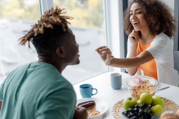 Cheerful young woman feeding her boyfriend in cafe