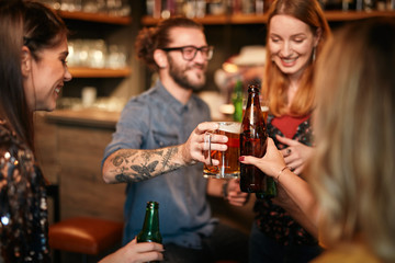 Friends standing in bar and toasting with beer.