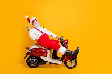 Full body photo of funny white hair santa in festive mood riding x-mas theme party by bike showing...